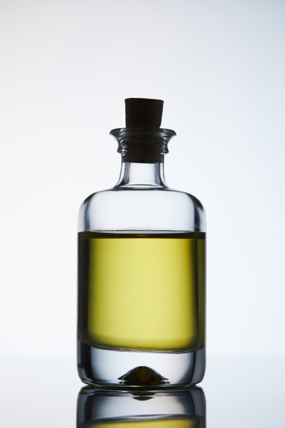 botella cerrada de aceite de masaje aromático de pie en la superficie reflectante
 - Foto, Imagen