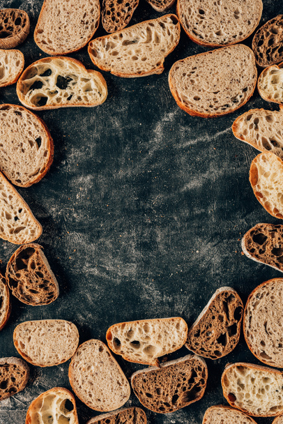 top view of arranged pieces of bread on dark tabletop with flour - Fotoğraf, Görsel
