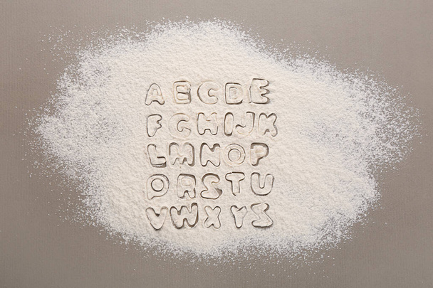 Silhouettes of alphabet letters on scattered flour - Фото, зображення
