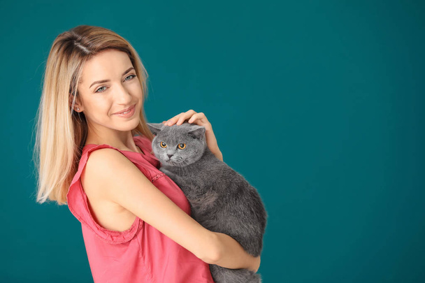 Young woman with cute pet cat on color background - Photo, Image