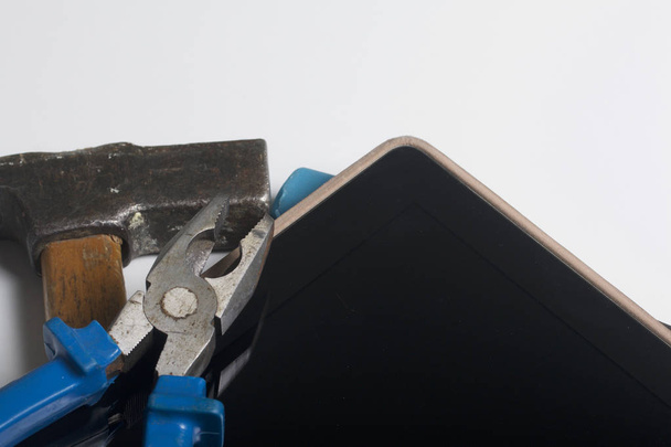 Tablet and working tools. On the white surface of the table is a tablet, skein, chisel and pliers. Destruction and repair of electronic devices. - Foto, Imagem