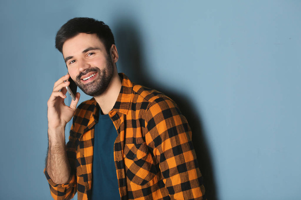 Young man talking on mobile phone against color background - Foto, afbeelding