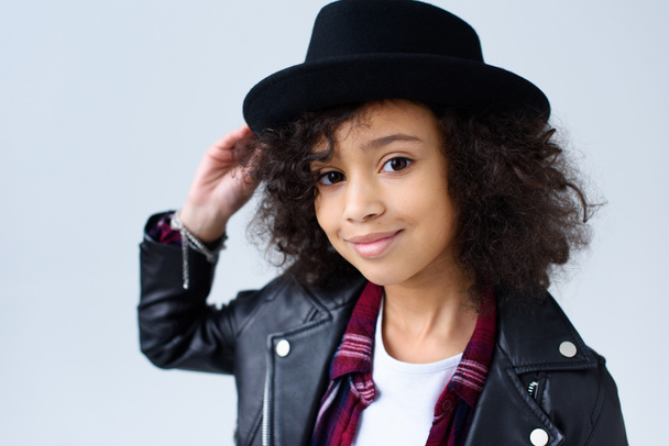 close-up portrait of adorable little child in leather jacket and hat looking at camera isolated on grey - Фото, зображення