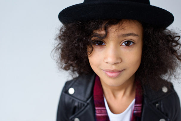 close-up portrait of beautiful little child in leather jacket and hat looking at camera isolated on grey - Fotografie, Obrázek