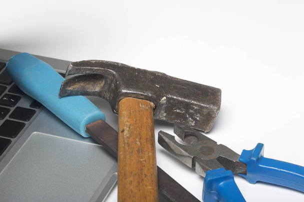 Laptop and work tools. On the white surface of the table is a tablet, skein, chisel and pliers. Destruction and repair of electronic devices. - Zdjęcie, obraz
