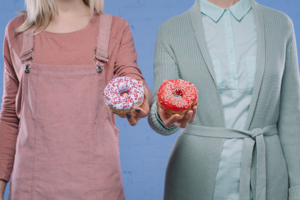 cropped shot of stylish women holding glazed doughnuts - Фото, зображення