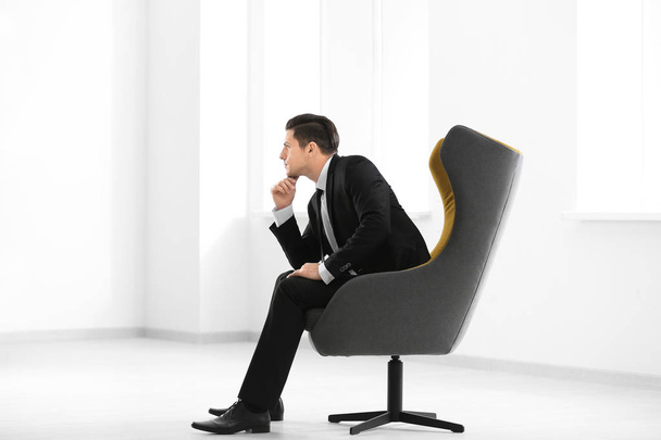 Handsome businessman sitting in comfortable armchair indoors - Valokuva, kuva