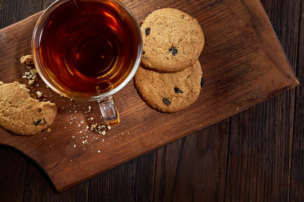 Cup of tea with cookies on a cutting board on a wooden background, top view - Φωτογραφία, εικόνα