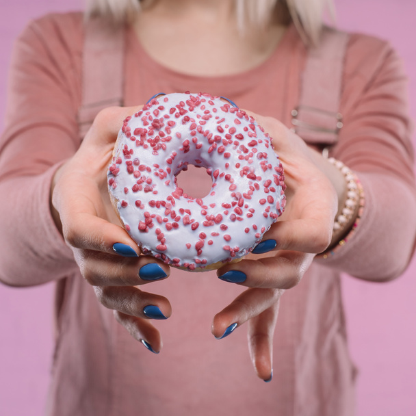 cropped shot of woman showing tasty glazed doughnut at camera - Foto, Imagen