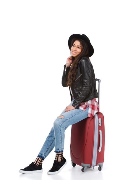 stylish young woman sitting on luggage isolated on white - Фото, зображення