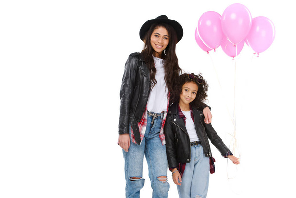 beautiful mother and daughter in similar clothes with pink balloons isolated on white - Foto, afbeelding