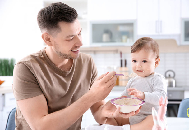 Father feeding his little son in kitchen - Valokuva, kuva
