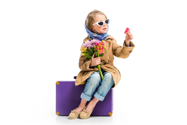Stylish kid in sunglasses and headscarf holding bouquet of flowers isolated on white - Foto, afbeelding