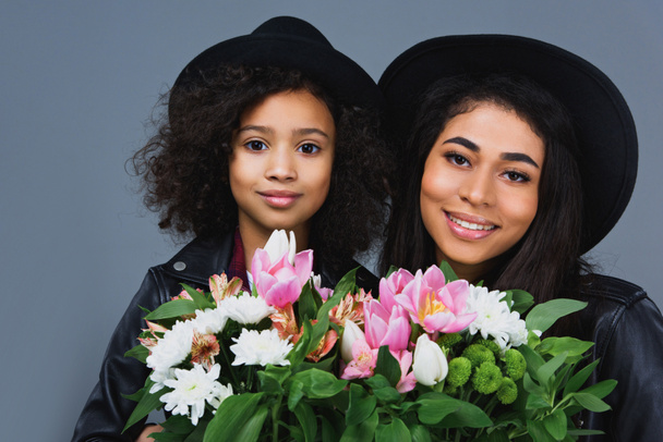 close-up portrait of mother and daughter with beautiful bouquets isolated on grey - Foto, Imagen