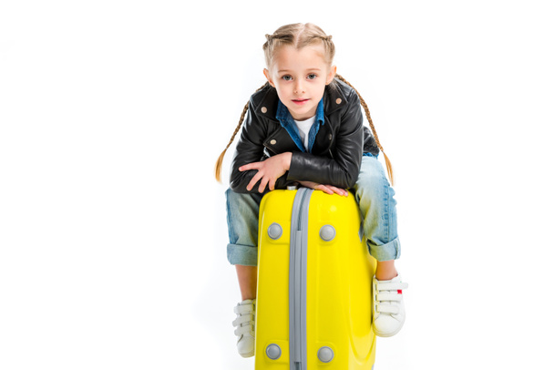 View of kid with pigtails sitting on yellow wheel suitcase isolated on white - Zdjęcie, obraz