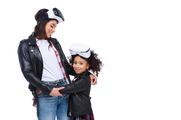 молодые стильные обнимающие мать и дочь в наушниках виртуальной реальности, изолированных на белом
 - Фото, изображение