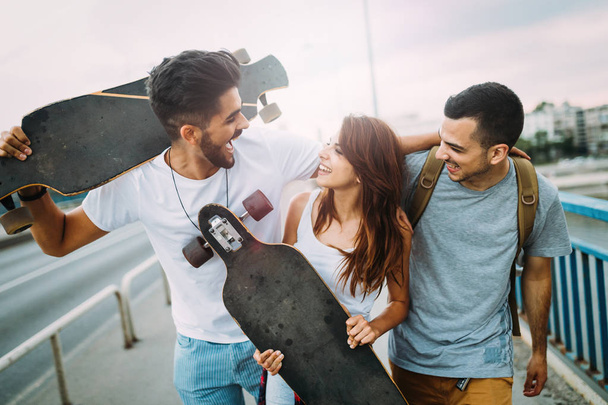 Group of happy friends hang out together carrying skateboards - Fotografie, Obrázek