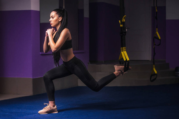 Mujer atractiva hace Crossfit con correas de fitness Trx en el estudio del gimnasio
 - Foto, imagen