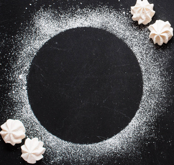 Sweet white meringue on a black wooden background, free space fo - Foto, afbeelding
