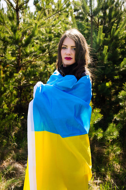 Το μοντέλο σε μαύρα ρούχα κρατά την σημαία της Ουκρανίας. Κάθετες φωτογραφίες - Φωτογραφία, εικόνα