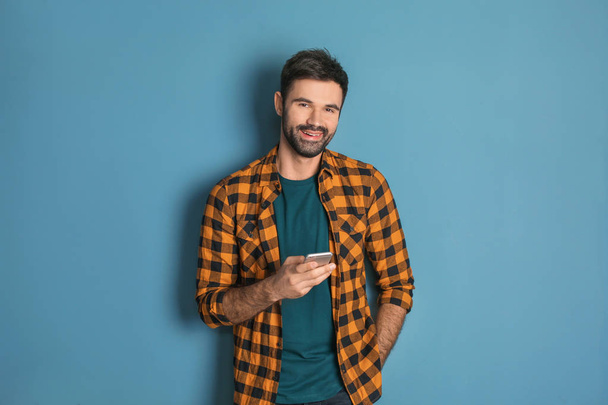 Young man using mobile phone on color background - Fotoğraf, Görsel