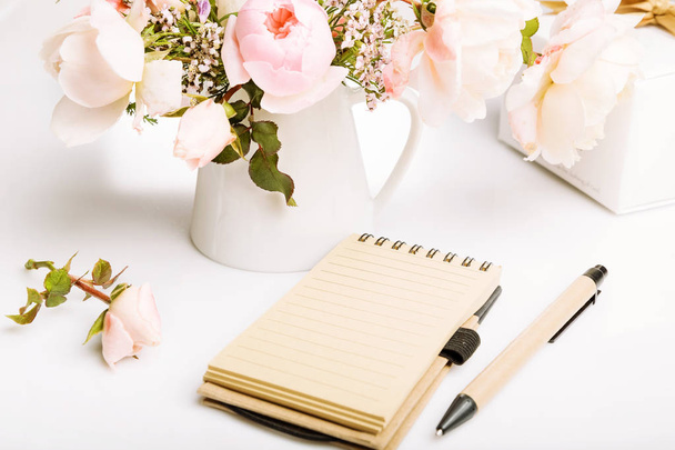 休日の美しい新鮮なピンク イングリッシュ ・ ローズ、ギフト カード、ノート、ペン、白い背景の上の鉛筆。誕生日、母の女性の結婚式の日の概念. - 写真・画像
