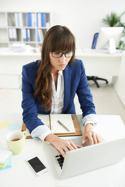 Mujer de negocios ocupada con el trabajo en el ordenador portátil en su mesa de oficina
 - Foto, Imagen