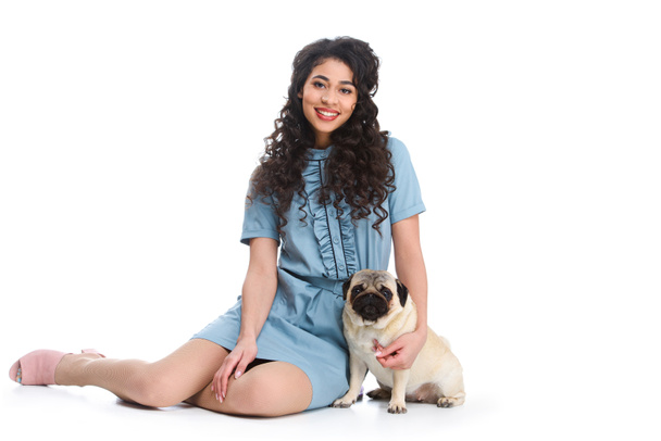 smiling young woman sitting on floor with pug isolated on white - Photo, Image