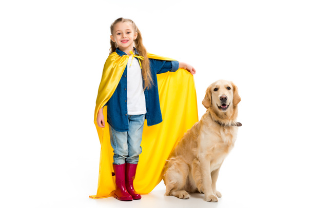 Supergirl en capa amarilla de pie con golden retriever al lado aislado en blanco
 - Foto, Imagen