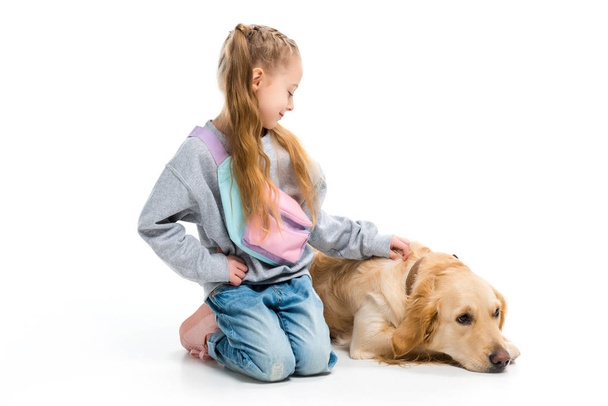 Стильна дитина погладжує лежачого собаку з коміром ізольовано на білому
 - Фото, зображення