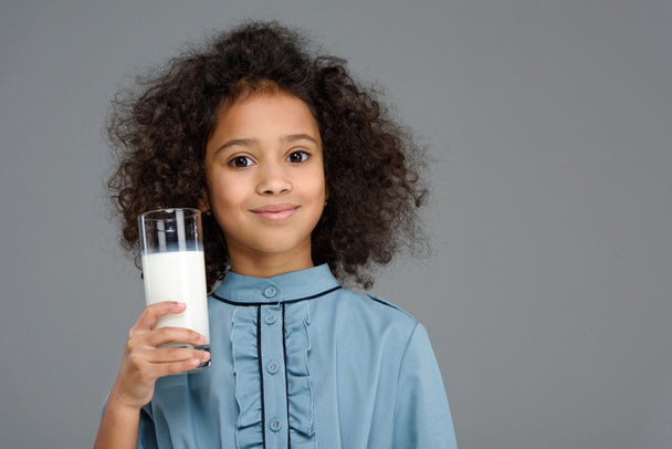 uśmiechający się małe dziecko z szklankę mleka na szarym tle - Zdjęcie, obraz