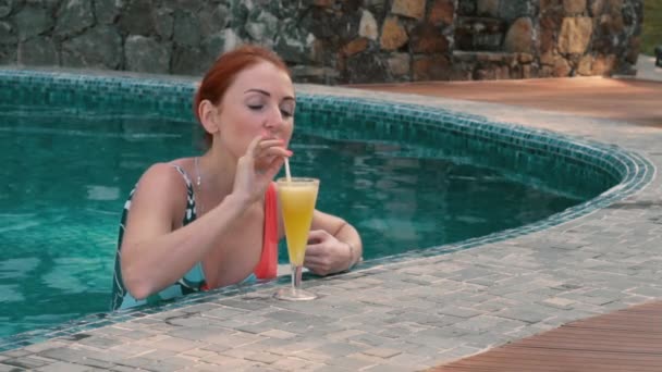 young woman drinks a cocktail in the pool - Felvétel, videó