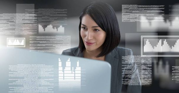 Digital composite of Businesswoman working on laptop with screen text interface - 写真・画像