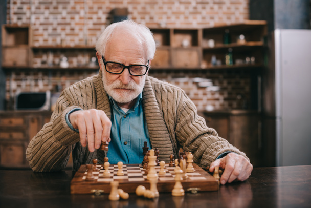 Sênior inteligente jogando xadrez sozinho
 - Foto, Imagem