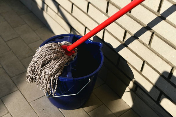Wet mop in blue bucket on tiled floor  - Photo, Image