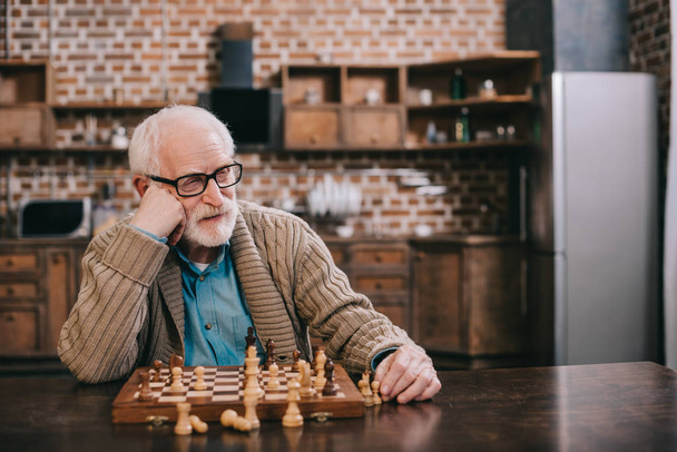 Bored senior man playing chess - Fotoğraf, Görsel