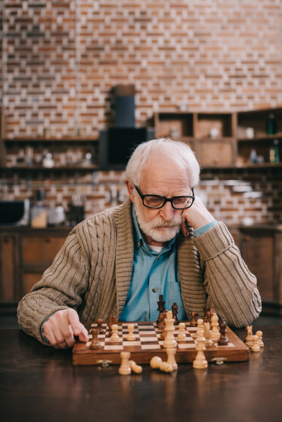 Pensativo anciano por tablero de ajedrez
 - Foto, Imagen