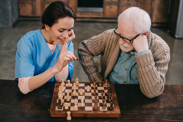 Top view of nurse and elder man playing chess - Photo, Image