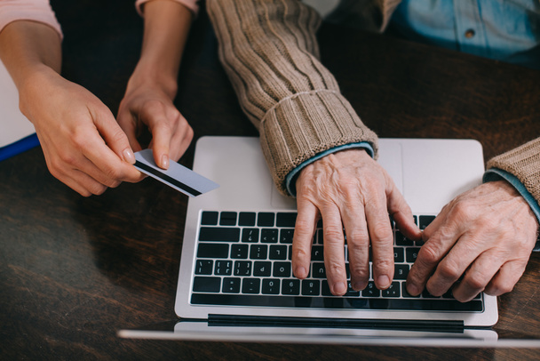 Close-Up Nézd nő és idősebb ember használ a laptop és a hitelkártya - Fotó, kép