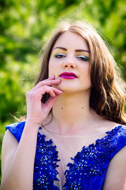 schöne Mode-Modell in einem Kleid in einem grünen Park im Sommer. auf dem Hintergrund des grünen Waldes. blaues Kleid. - Foto, Bild