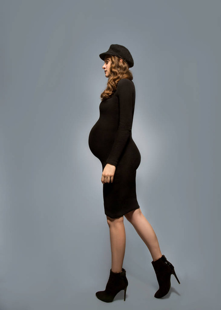 beautiful fashionable girl pregnant in studio stands posing - Foto, afbeelding