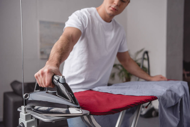 cropped image of man taking iron for ironing shirt - Foto, afbeelding