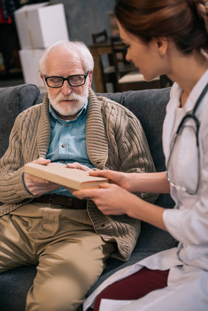 Homem mais velho tomando livro de médico feminino
 - Foto, Imagem