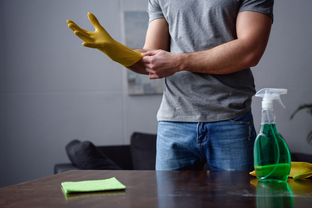 обрізане зображення чоловіка в гумових рукавичках для прибирання вітальні
 - Фото, зображення