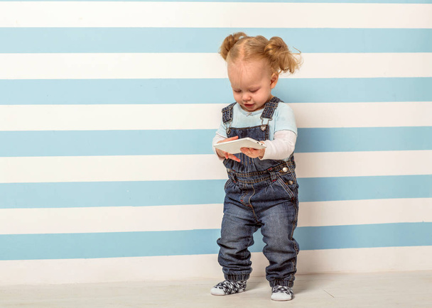 little girl stands near a striped background - Zdjęcie, obraz