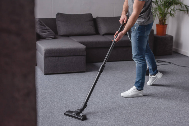 cropped image of man cleaning carpet with vacuum cleaner in living room - Φωτογραφία, εικόνα