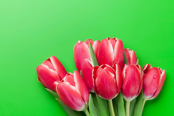 Bouquet de tulipes rouges sur fond vert. Carte de vœux. Vue de dessus avec espace pour les salutations
 - Photo, image