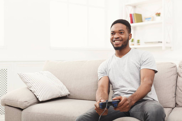 Χαρούμενος νεαρός άνδρας Αφροαμερικανός στο σπίτι παίζοντας βιντεοπαιχνίδια - Φωτογραφία, εικόνα