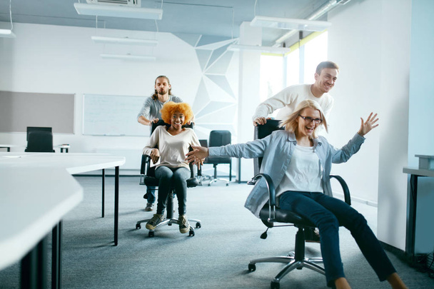 Office. People Having Fun And Racing On Chairs. - Foto, Imagen