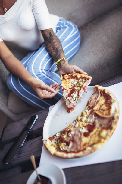 junge tätowierte Kubanerin isst Pizza im Café - Foto, Bild